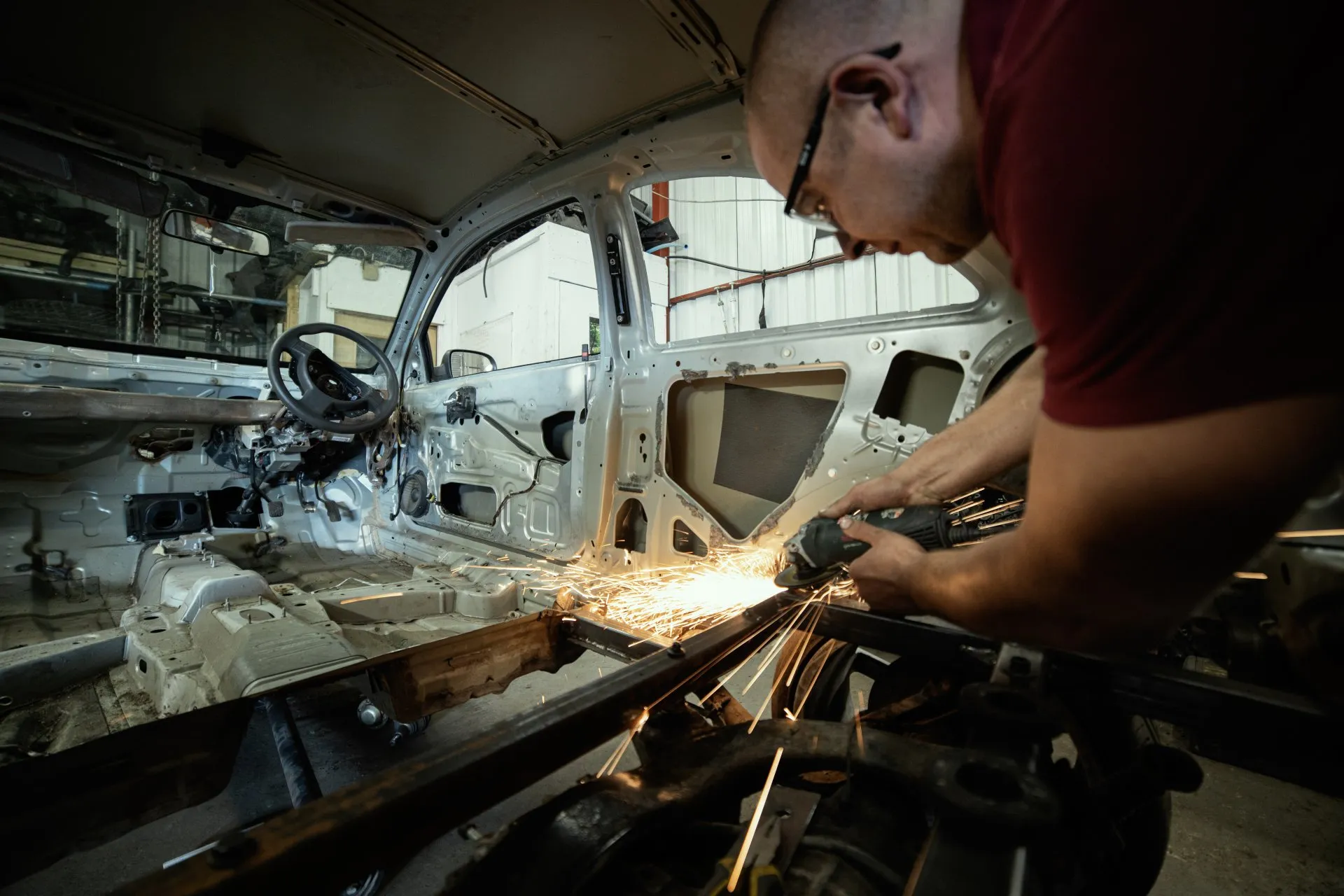 Mechanic grinding inside a stripped cabin