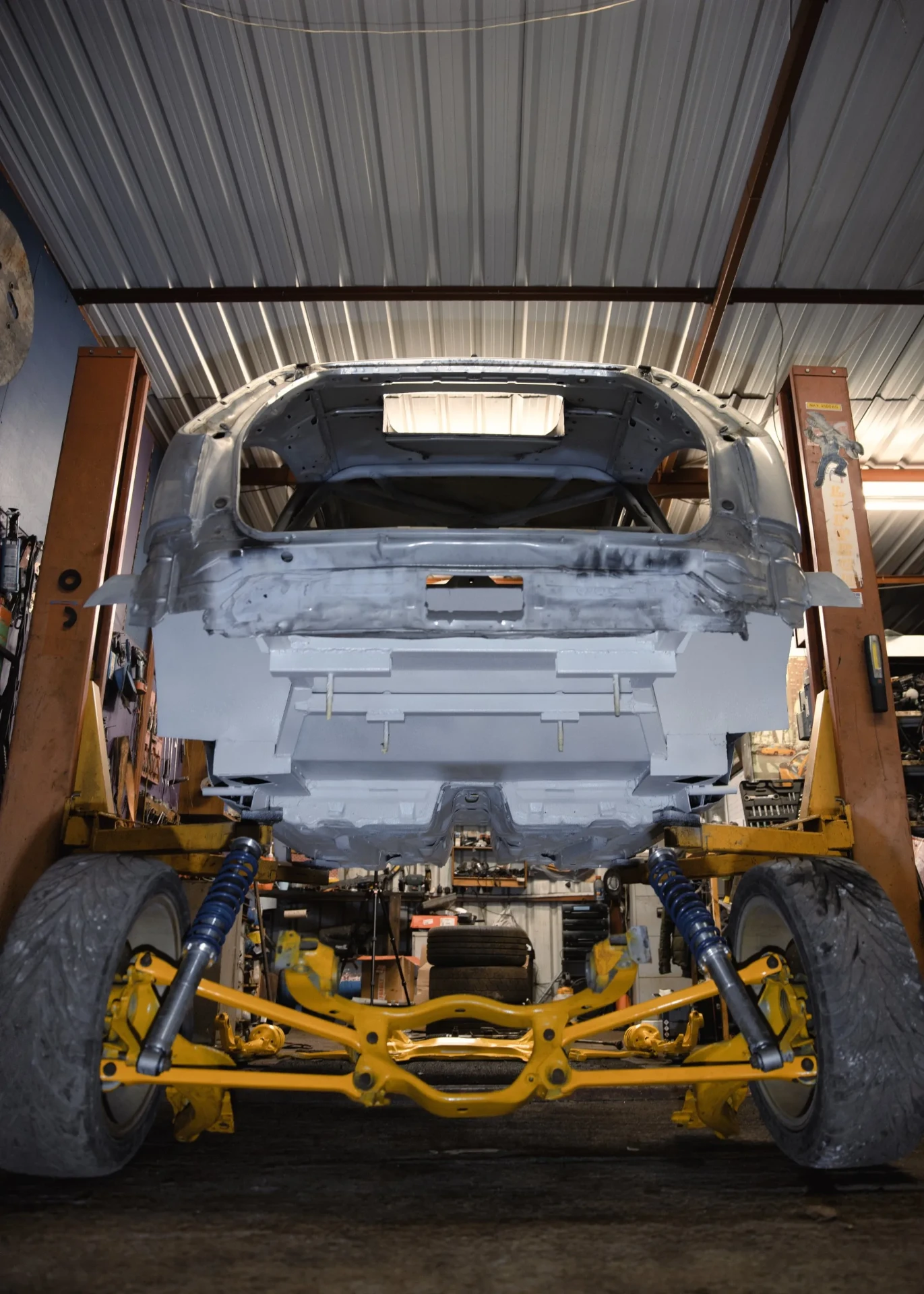 Rear underbody view of shell on lift with yellow subframe fitted