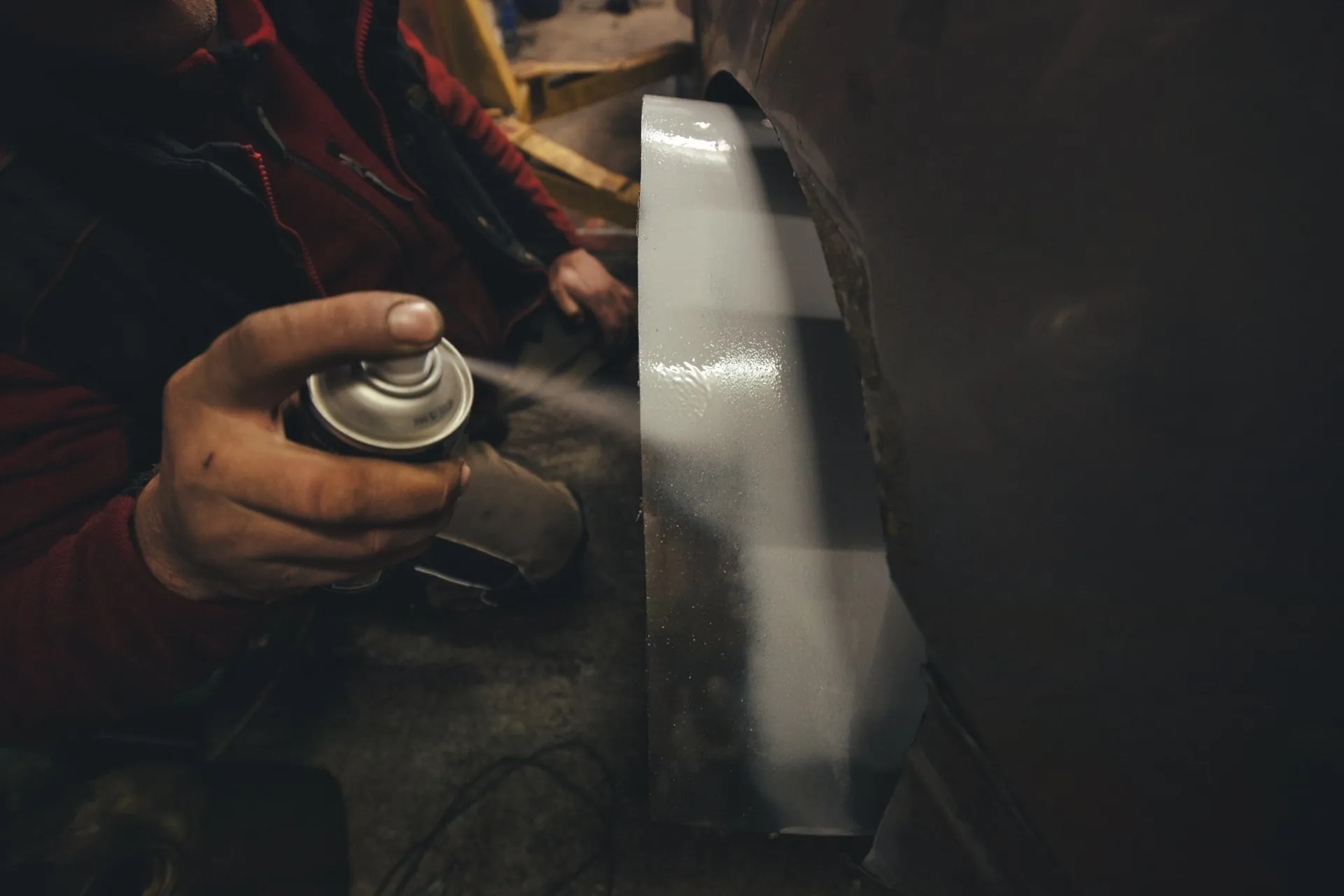 Mechanic spray priming a metal panel in the workshop