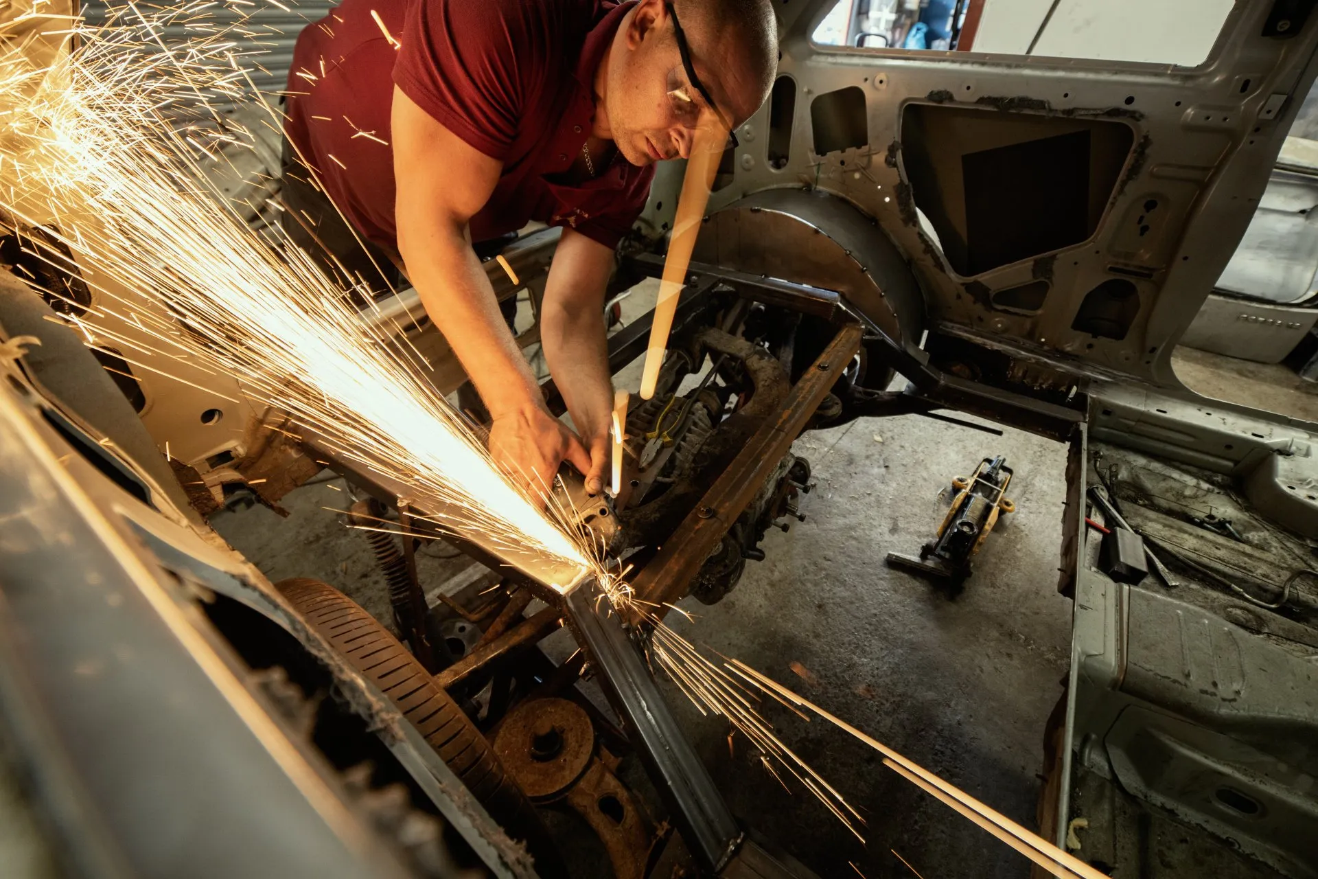 Mechanic cutting chassis rail with an angle grinder